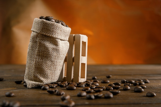 Foto granos de café en una bolsa pequeña sobre una mesa de madera