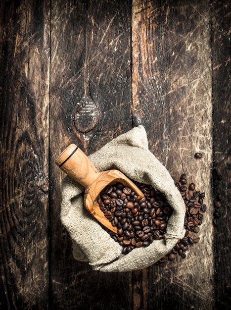 Granos de café en una bolsa. Sobre un fondo de madera.