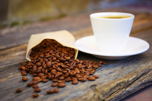 Los granos de café se caen de la bolsa sobre una vieja mesa de madera.