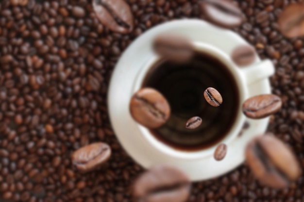 Granos de café caen en una taza de café Bebida energética cafeína Enfoque selectivo