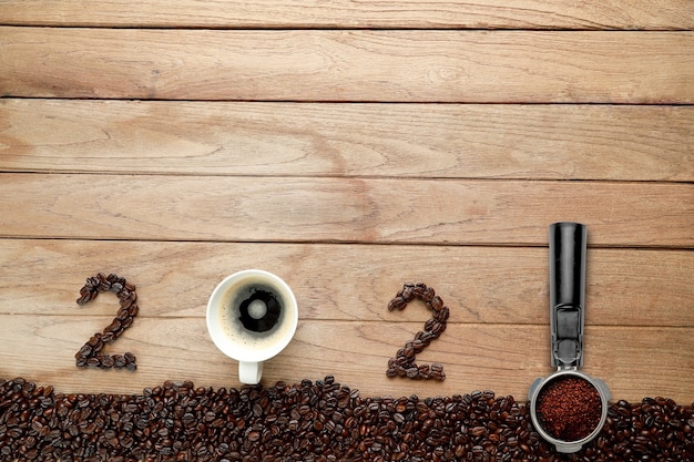 Foto granos de café y café caliente en una taza blanca y texto 2021 para el concepto de feliz año nuevo.