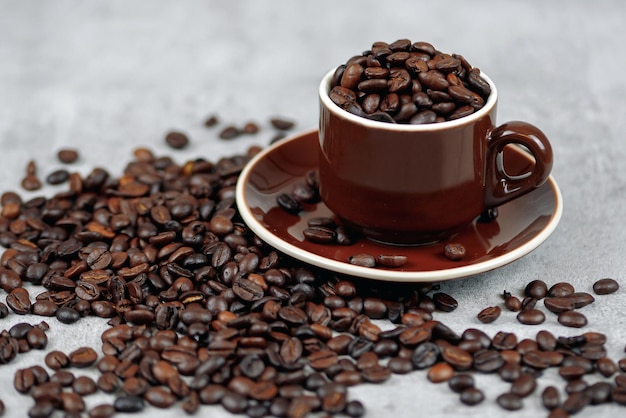 Granos de café y café en una taza sobre un fondo gris