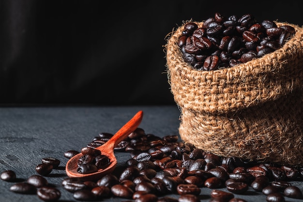 Granos de café crudos en un bolso del saco en un fondo negro.