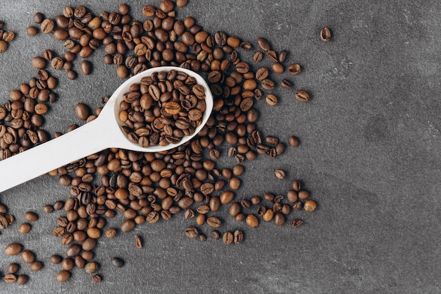 Granos de café en cuchara de madera aislado sobre fondo oscuro