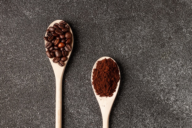 Granos de café en la cuchara de madera. Hormigón oscuro