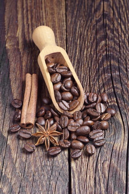 Granos de café y cuchara de madera sobre mesa de madera oscura.