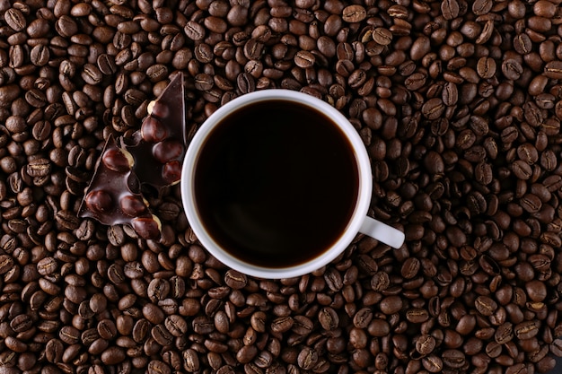 Granos de café dispersos, una taza y chocolate negro.