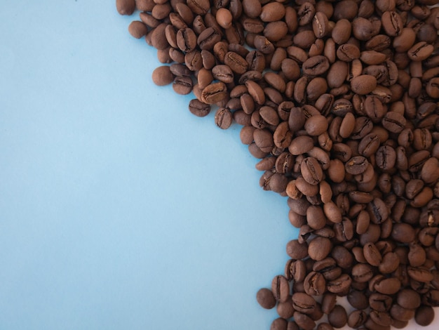 Granos de café esparcidos en azul en un espacio de forma de onda para texto y espacio de copia