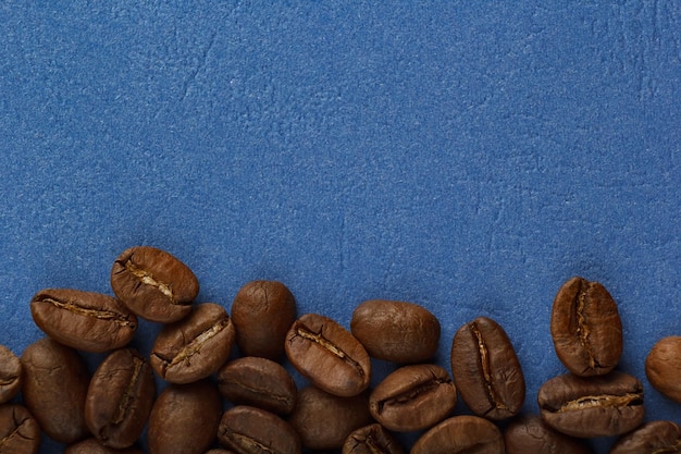 Foto los granos de café están esparcidos en un fondo azul desde el borde del marco fondo azul de café