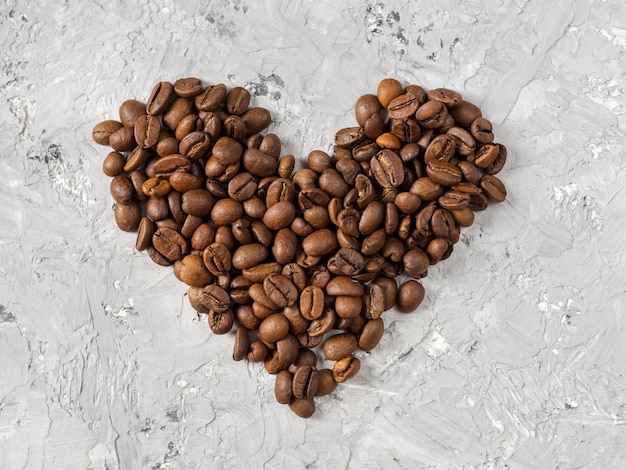 Los granos de café están sobre la mesa en forma de corazón.