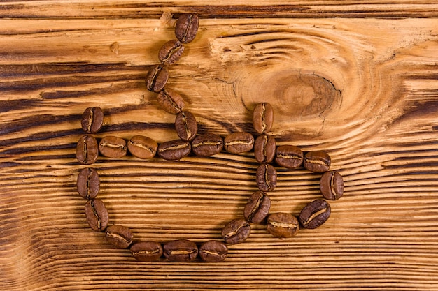 Foto granos de café en forma de taza sobre una mesa de madera rústica. vista superior