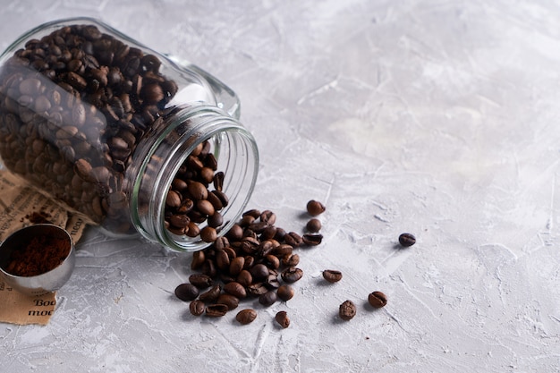 Granos de café en un frasco de vidrio sobre una mesa gris