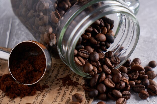 Granos de café en un frasco de vidrio sobre una mesa gris