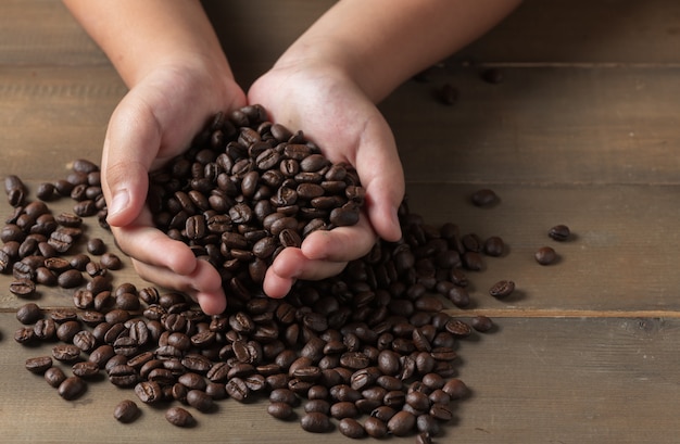 Granos de café frescos en manos niño, concepto de bebida