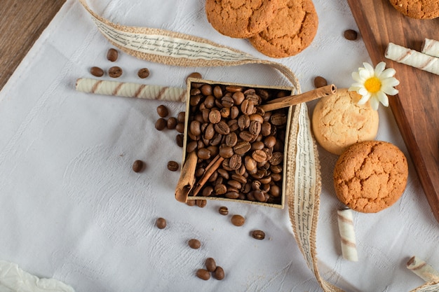 Granos de café y galletas en mantel azul. vista superior