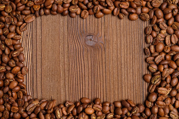 Los granos de café hacen un marco para un lugar con texto sobre un fondo de madera.