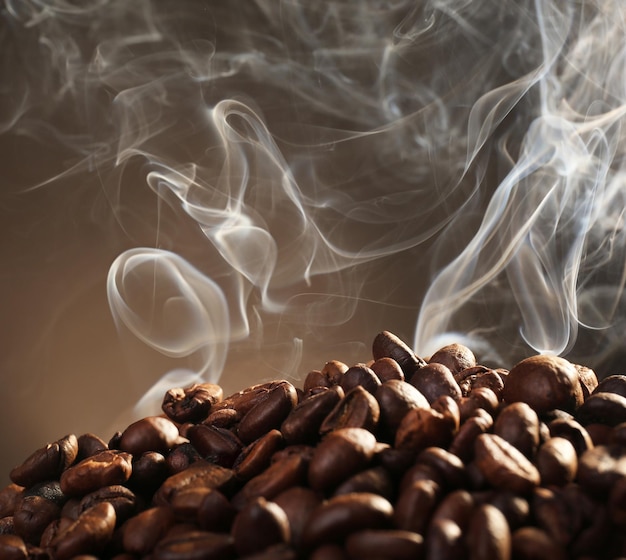 Granos de café con humo sobre fondo oscuro