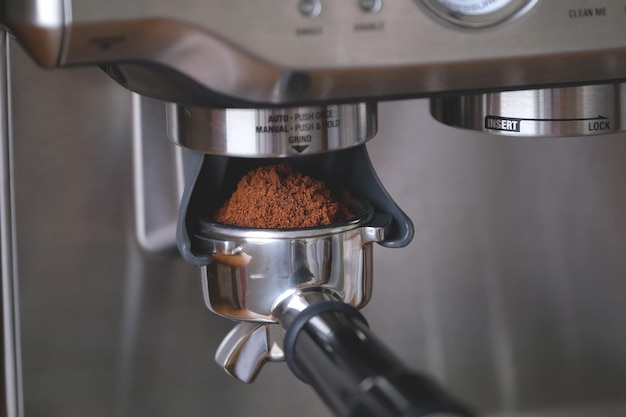 Foto granos de café molido en un portafiltro de metal en un primer plano de la máquina de café haciendo café espresso