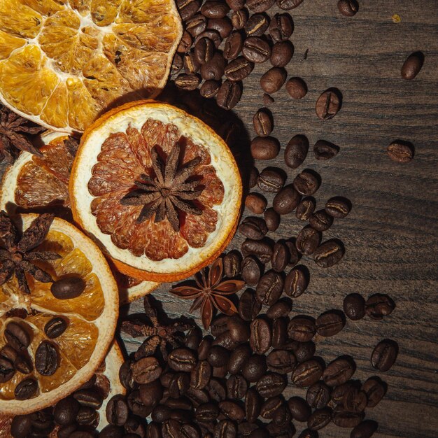 Granos de café con naranja seca y canela sobre un fondo de madera