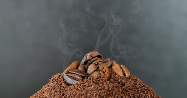 Granos de café naturales en café molido con humo visible