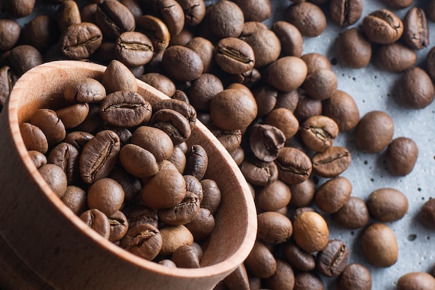 Granos de café oscuros en una taza de madera. Imagen simbólica. Fondo de madera rústica. De cerca. Copie el espacio.