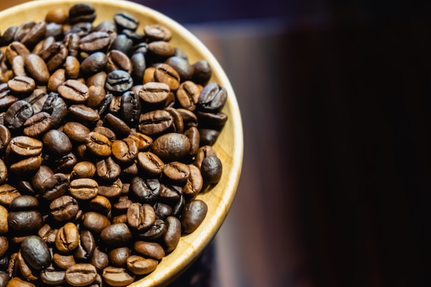 Los granos de café en plato de madera.