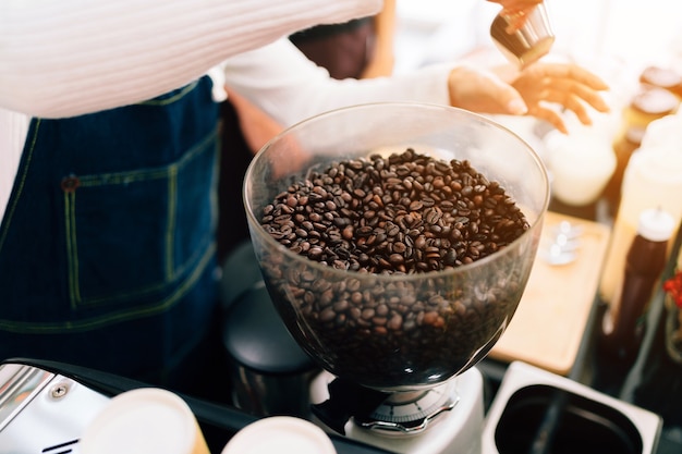 Granos de café de primer plano dentro de la máquina de molienda de café eléctrica.