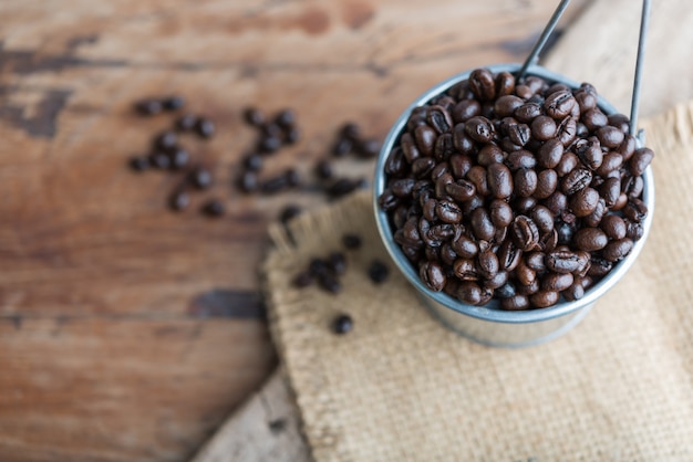 Granos de café rosted en bote galvanizado sobre fondo de madera grunge