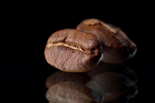 Granos de café sobre un fondo negro Café sobre un fondo negro con reflejo