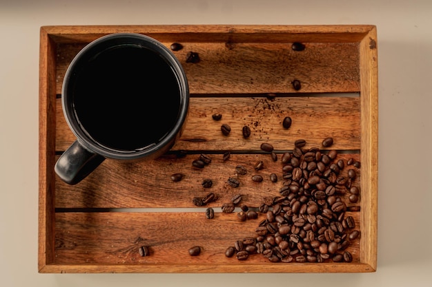 Granos de café y taza en una bandeja y mesa de madera, decoración de cafetería