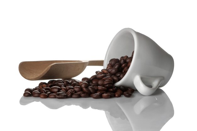 Granos de café en una taza blanca y una cuchara