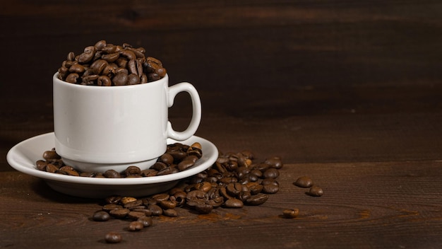 Granos de café en una taza blanca y plato Espacio de copia Fondo marrón