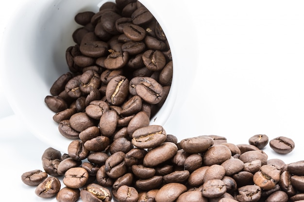 Granos de café en taza de café sobre fondo blanco