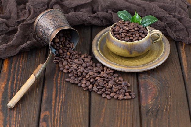 granos de café en una taza y una cafetera en una mesa de madera