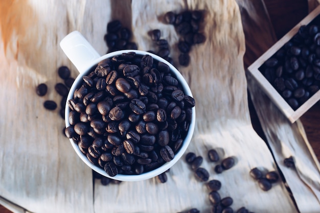 Granos de café con una taza en la mesa