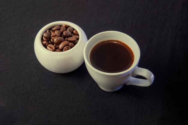 Granos de café en tazas sobre un fondo negro