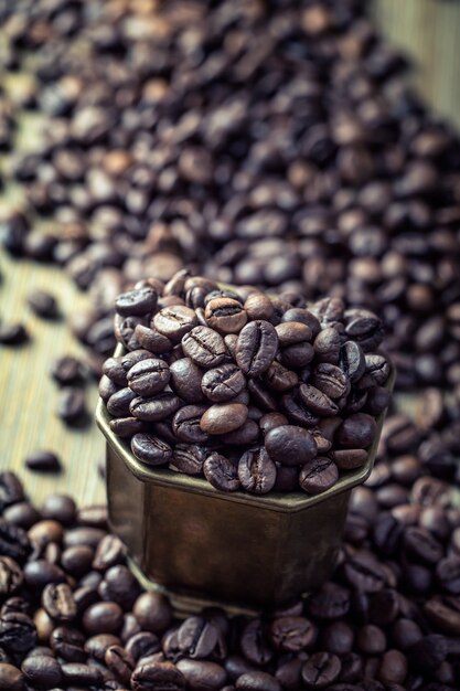 Granos de café en un tazón de bronce - de cerca.