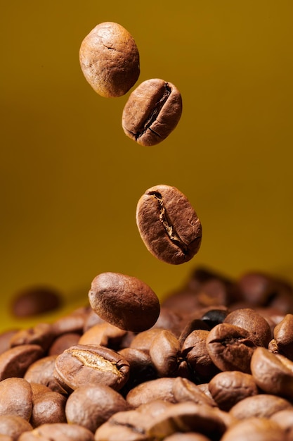 Granos de café tostados aislados de cerca en el camino de recorte de fondo amarillo