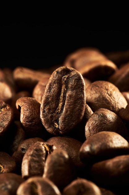 Granos de café tostados aislados de cerca en el camino de recorte de fondo negro