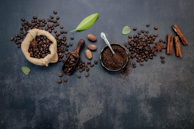 Granos de café tostados con café en polvo e ingredientes sabrosos para preparar un café sabroso en piedra oscura.