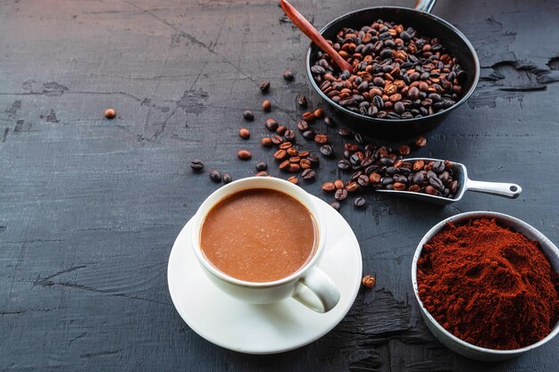 Granos de café tostados con café en polvo y tazas de café.