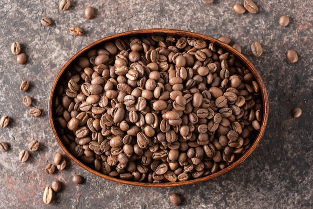 Foto granos de café tostados en una caja de madera sobre un fondo oscuro.