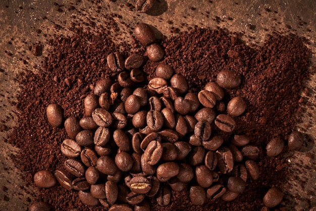 Granos de café tostados diferentes tipos de tierra y todo aislado de cerca sobre fondo marrón grunge