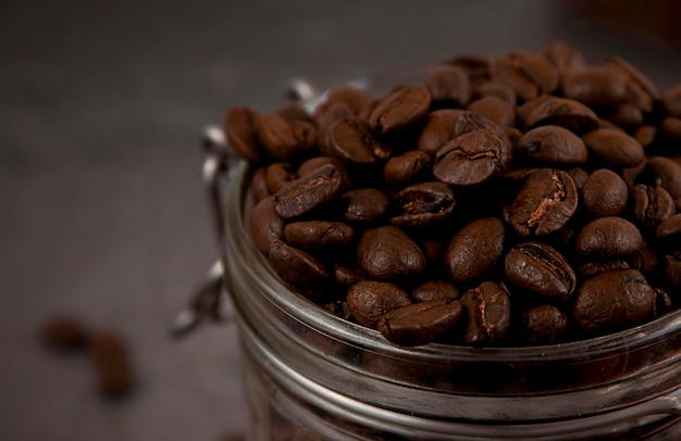 Granos de café tostados en un frasco de vidrio de cerca Copiar espacio