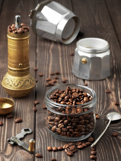 Granos de café tostados en un frasco de vidrio y granos de café dispersos en una mesa de madera marrón