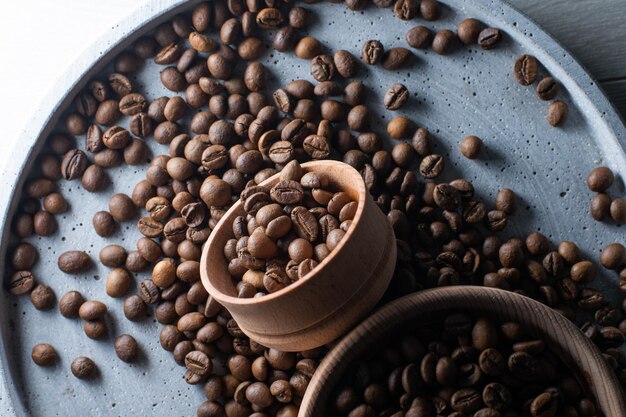 Granos de café tostados marrones cayendo sobre una pila. Representa el desayuno, la energía, la frescura o el gran aroma, Volando sobre fondo oscuro con espacio para copiar, primer plano.