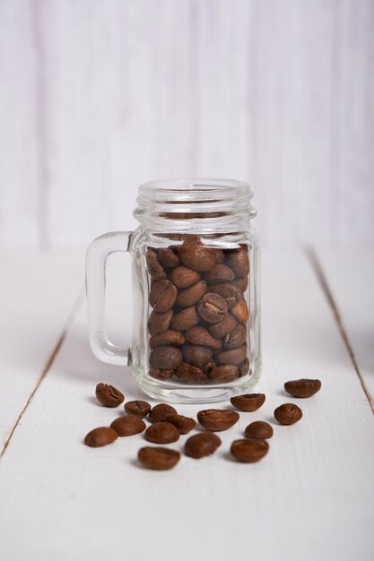 Granos de café tostados naturales en un pequeño tarro de cristal transparente