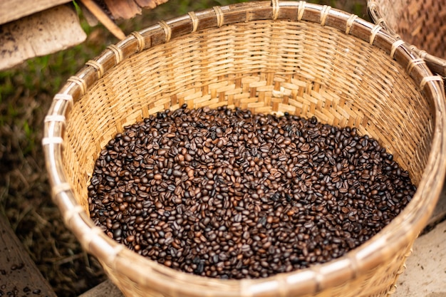 Granos de café tostados oscuros en una cesta de bambú de la armadura.