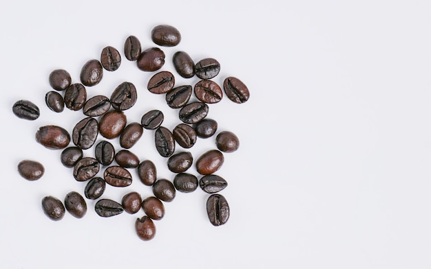 Granos de café tostados con piel brillante Ha sido cuidadosamente seleccionado Listo para moler y llevar a la infusión Tomado desde un ángulo alto con el aroma del café sobre un fondo blanco en el estudio