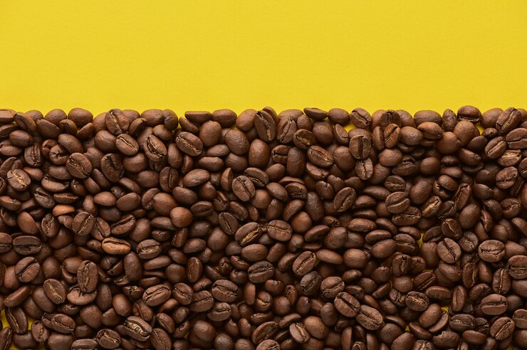 Granos de café tostados sobre fondo amarillo con espacio de copia vista superior de cerca